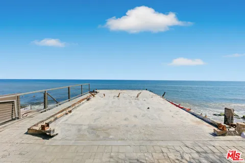 a living room with stainless steel appliances furniture and a kitchen view