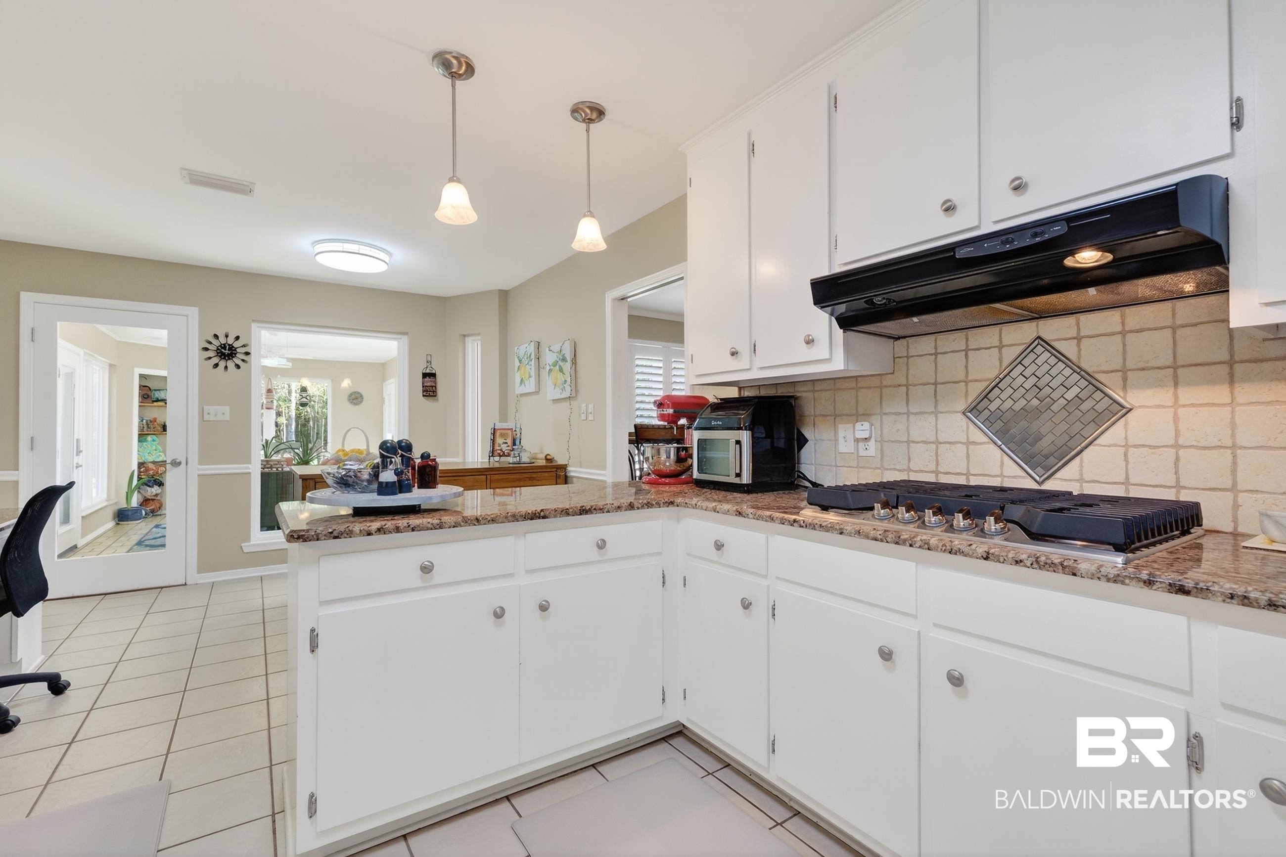 1271 Spring Valley Drive South Mobile, AL 36693 - Photo 16 of 56 Kitchen with a peninsula, white cabinets, decorative backsplash, light stone counters, and light tile patterned floors