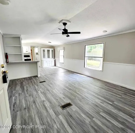 a view of an empty room with a window and wooden floor