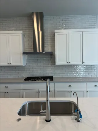 a large kitchen with stainless steel appliances a large counter top a stove and a refrigerator