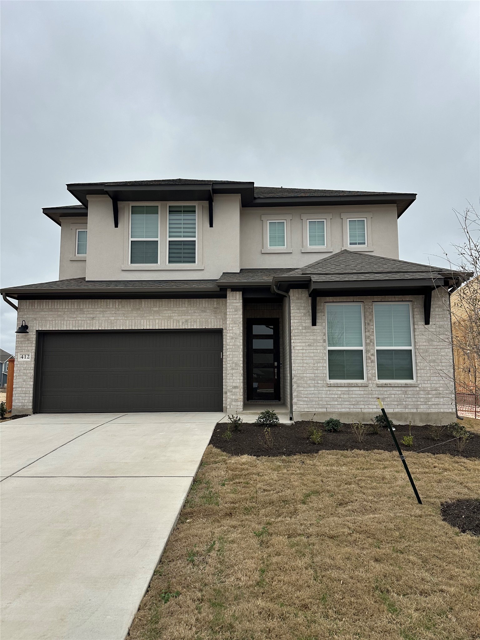 412 Lariat Loop Liberty Hill, TX 78642 - Photo 2 of 38 Prairie-style home with a garage, driveway, brick siding, and stucco siding