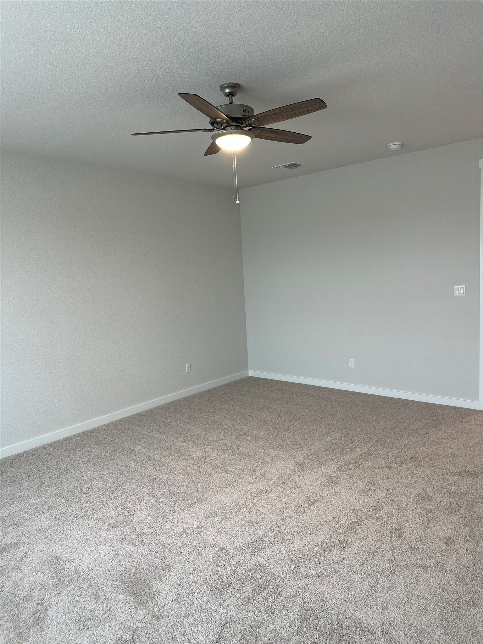 412 Lariat Loop Liberty Hill, TX 78642 - Photo 27 of 38 Carpeted empty room with visible vents, ceiling fan, a textured ceiling, and baseboards