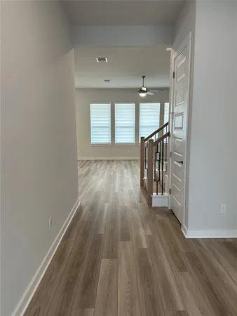 a view of an empty room with wooden floor and a window