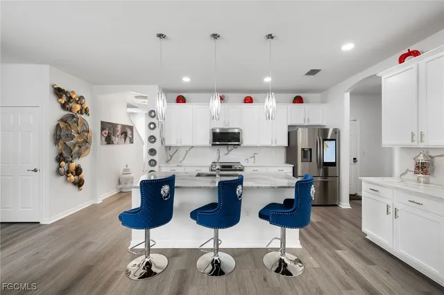 a kitchen with stainless steel appliances kitchen island granite countertop a refrigerator a stove a sink dishwasher and a dining table with wooden floor