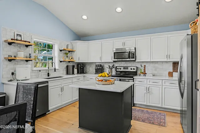 a kitchen with stainless steel appliances granite countertop a stove top oven a sink a microwave and cabinets