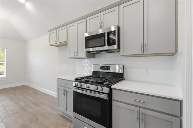 a kitchen with stainless steel appliances granite countertop white cabinets and a stove top oven