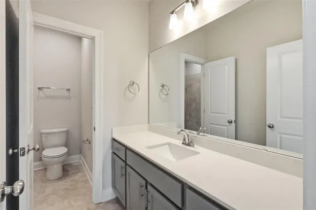 a bathroom with a sink a toilet and a large mirror