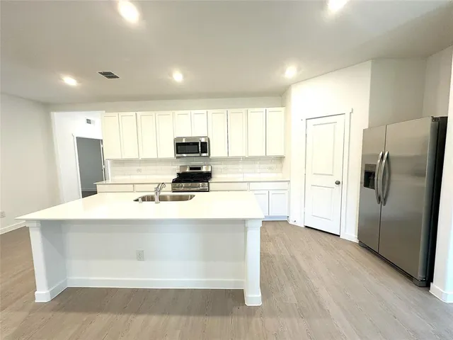 a kitchen with kitchen island a refrigerator sink and cabinets