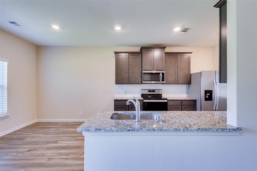 2256 Cashmere Way Princeton, TX 75407 - Photo 11 of 36 a kitchen with stainless steel appliances granite countertop a sink a stove and a microwave