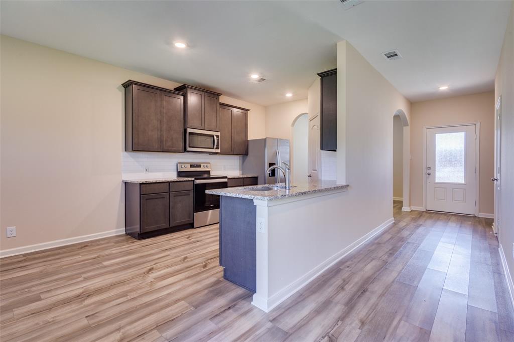 2256 Cashmere Way Princeton, TX 75407 - Photo 12 of 36 a kitchen with stainless steel appliances kitchen island wooden cabinets and granite counter tops