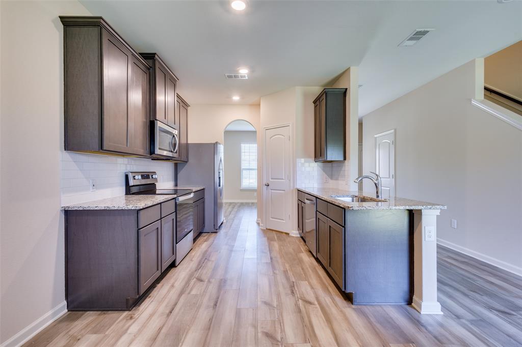 2256 Cashmere Way Princeton, TX 75407 - Photo 13 of 36 a large kitchen with stainless steel appliances granite countertop a stove a sink dishwasher a refrigerator and wooden floor