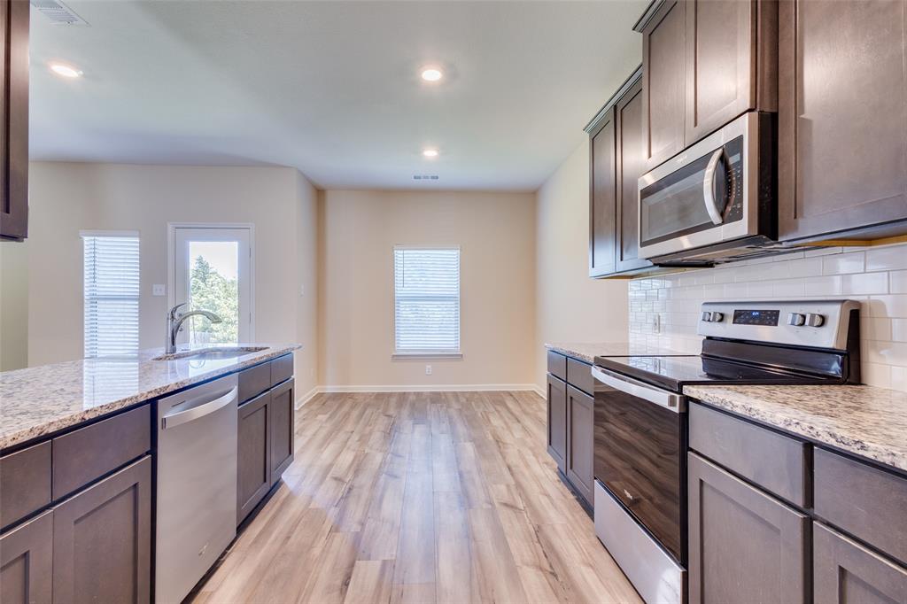 2256 Cashmere Way Princeton, TX 75407 - Photo 14 of 36 a kitchen with stainless steel appliances granite countertop wooden cabinets a stove top oven a sink and dishwasher next to a window