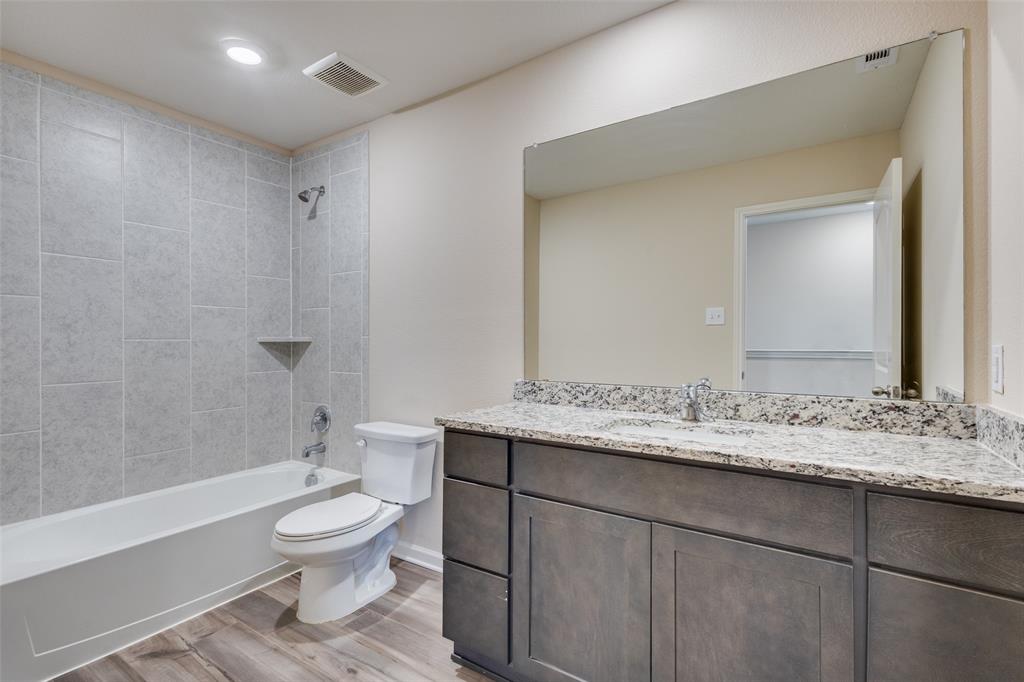 2256 Cashmere Way Princeton, TX 75407 - Photo 22 of 36 a bathroom with a granite countertop sink toilet a large mirror a shower and a bathtub