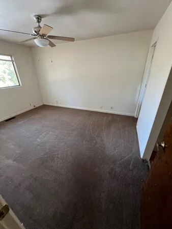 an empty room with windows and fan