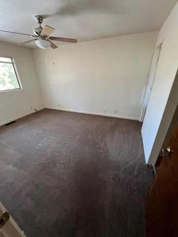 an empty room with windows and fan