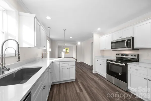 a large kitchen with stainless steel appliances granite countertop a sink a stove top oven a counter space and cabinets