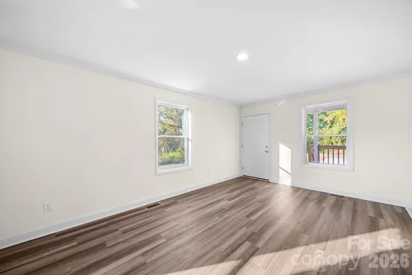 an empty room with wooden floor and windows