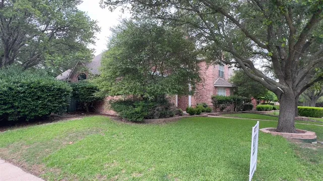 a front view of a house with a yard and a tree