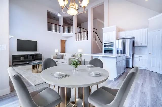 a kitchen with stainless steel appliances granite countertop a dining table chairs workspace room and wooden floor