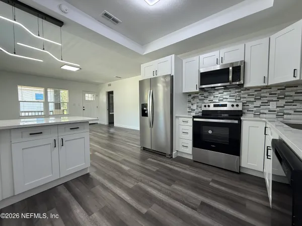 a large kitchen with stainless steel appliances granite countertop a stove and a refrigerator