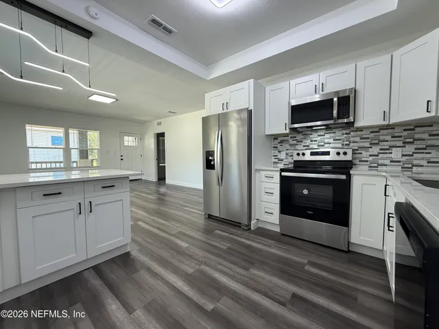 a large kitchen with stainless steel appliances granite countertop a stove and a refrigerator