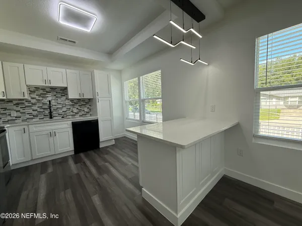 a kitchen with a sink cabinets wooden floor and a window