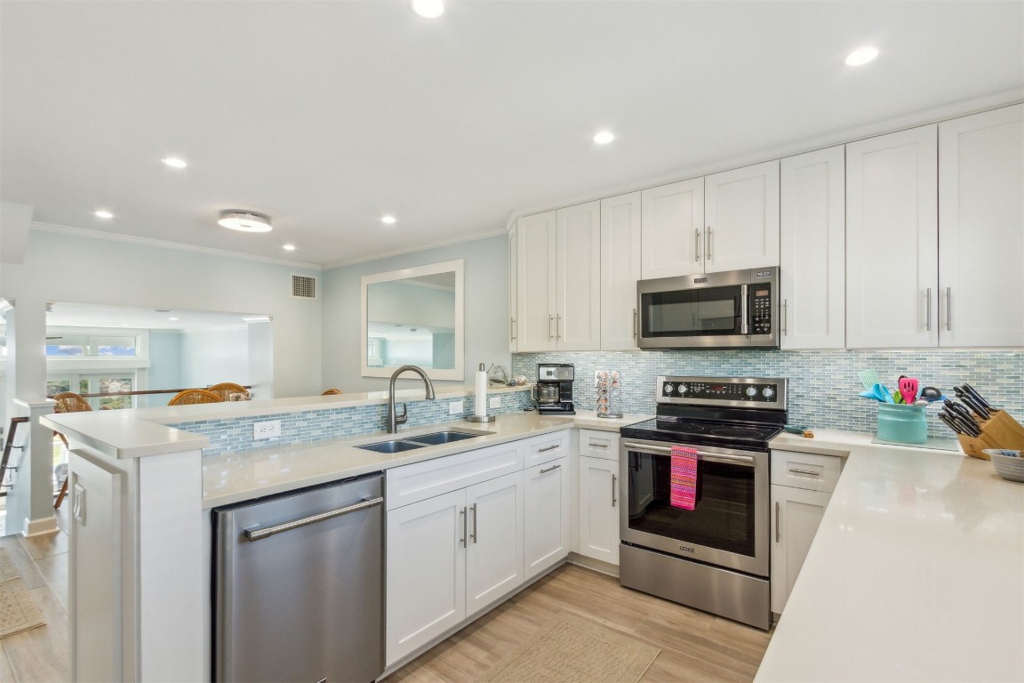 95078 Sandpiper Loop Fernandina Beach, FL 32034 - Photo 3 of 38 a kitchen with stainless steel appliances granite countertop a sink dishwasher stove and white cabinets with wooden floor