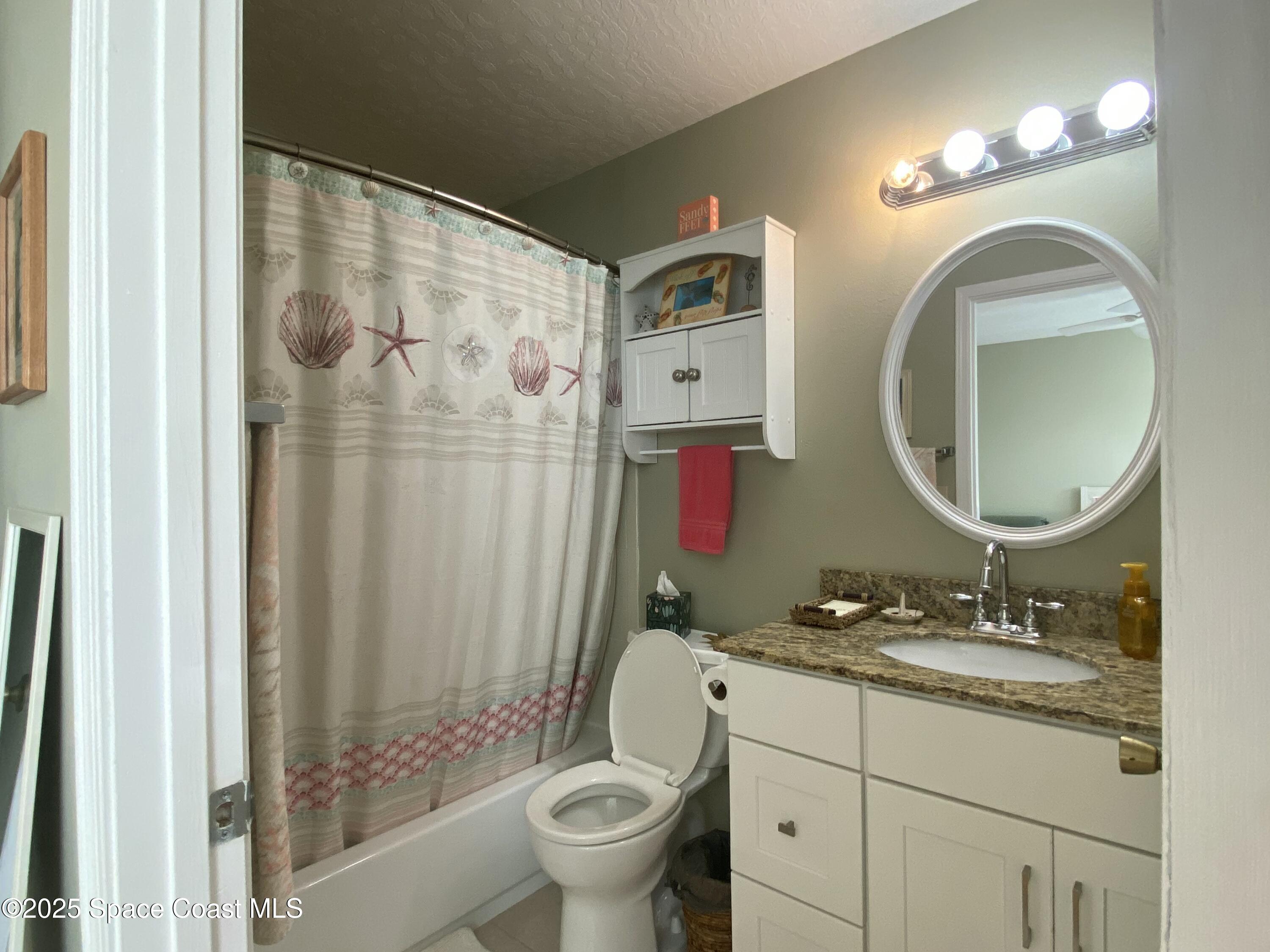 7667 North Wickham Road, Unit 1116 Melbourne, FL 32940 - Photo 22 of 34 a bathroom with a granite countertop toilet a sink and a mirror