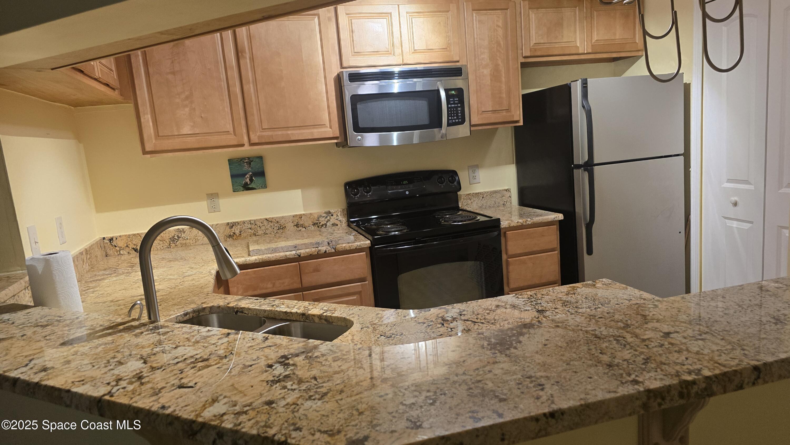 7667 North Wickham Road, Unit 1116 Melbourne, FL 32940 - Photo 5 of 34 a kitchen with a refrigerator and a stove top oven