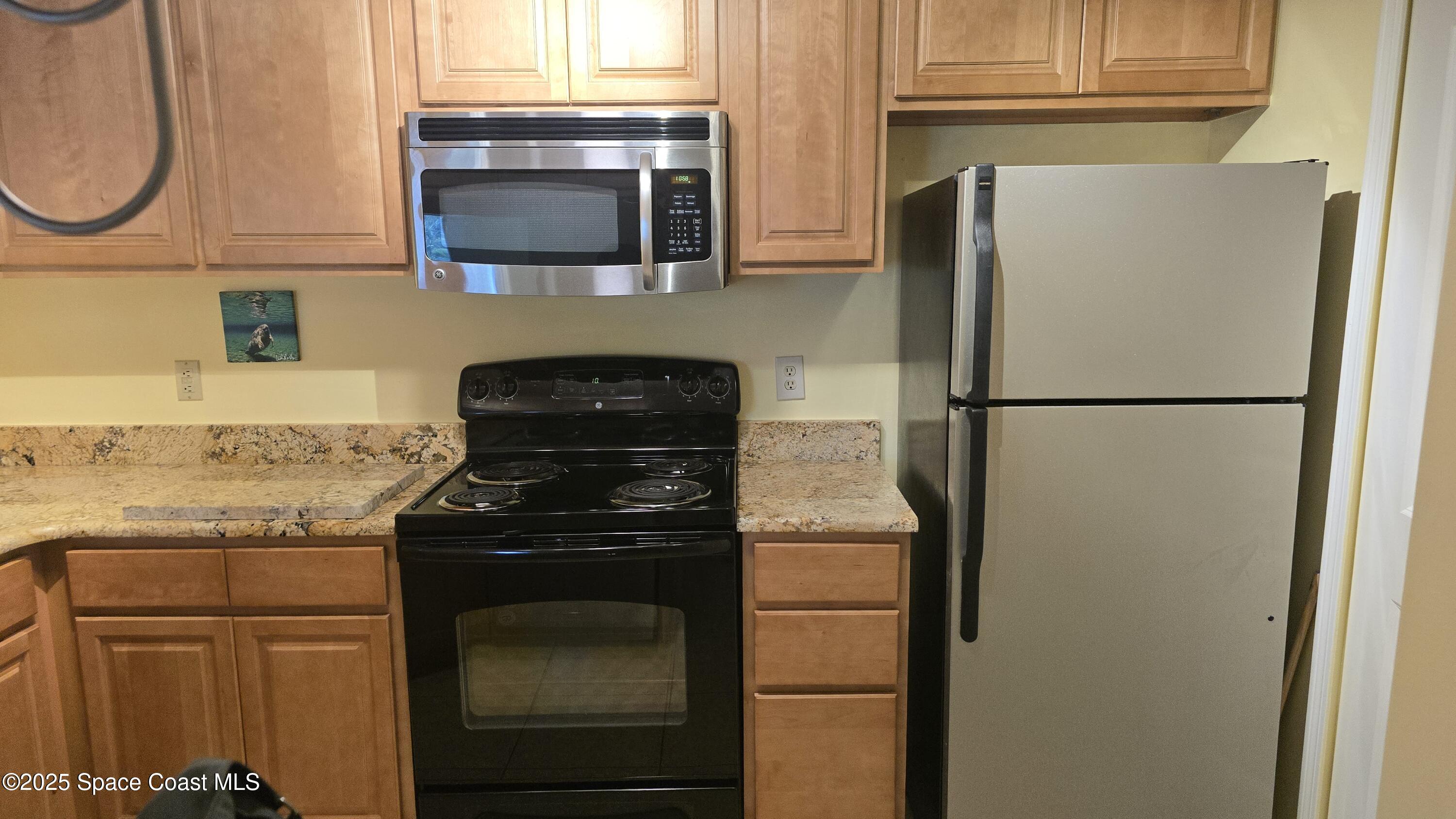 7667 North Wickham Road, Unit 1116 Melbourne, FL 32940 - Photo 6 of 34 a kitchen with a refrigerator and a stove top oven