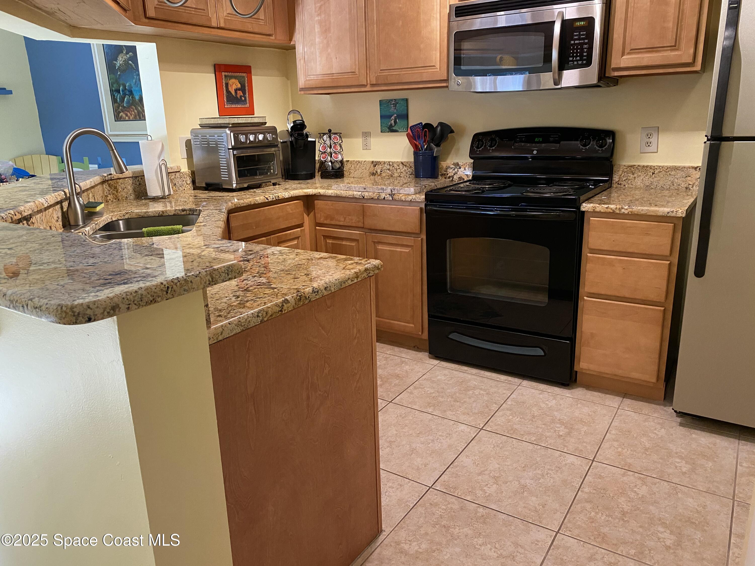 7667 North Wickham Road, Unit 1116 Melbourne, FL 32940 - Photo 7 of 34 a kitchen with stainless steel appliances granite countertop a stove a sink and a microwave