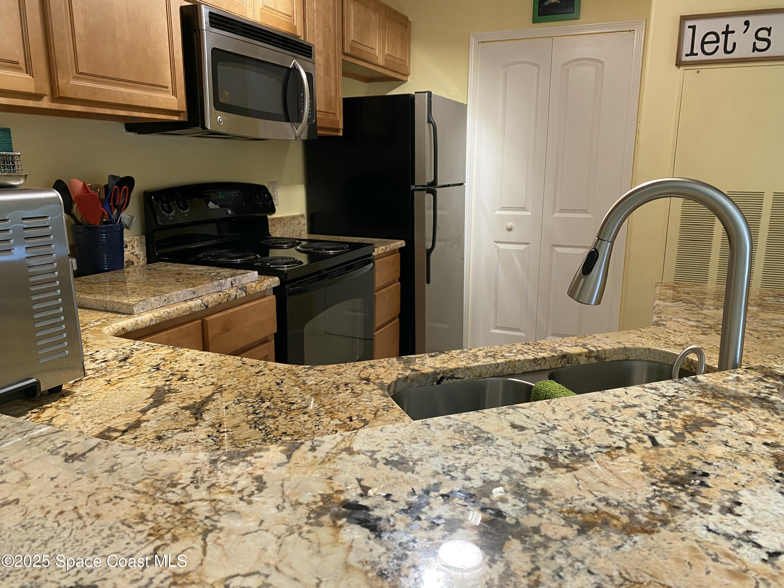 7667 North Wickham Road, Unit 1116 Melbourne, FL 32940 - Photo 8 of 34 a kitchen with granite countertop a refrigerator and a stove top oven
