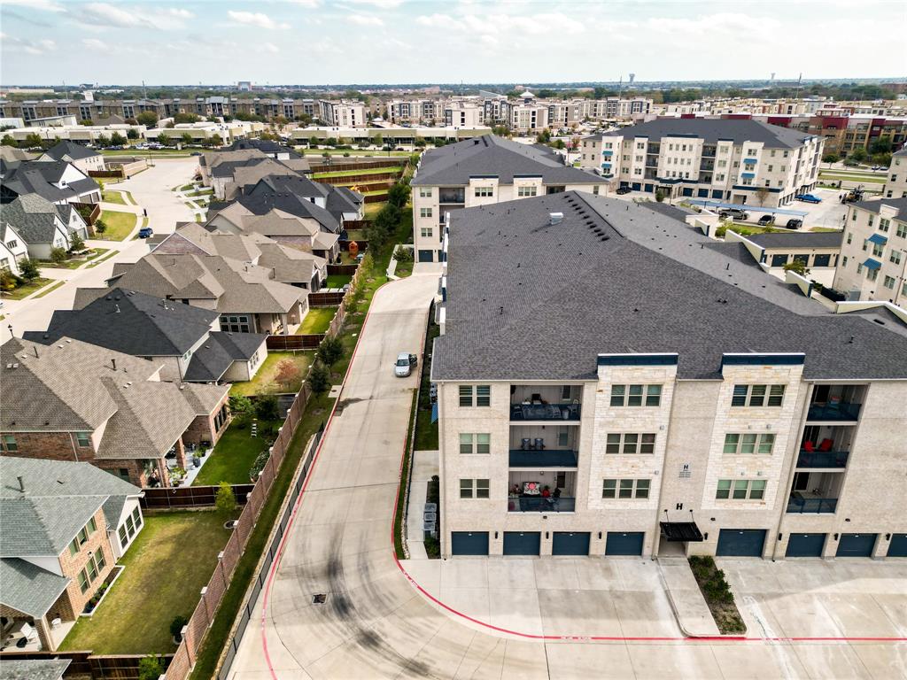 651 Watters Road, Unit 8204 Allen, TX 75013 - Photo 8 of 11 Contemporary apartment building with stone and siding exterior, private balconies, and integrated garage spaces