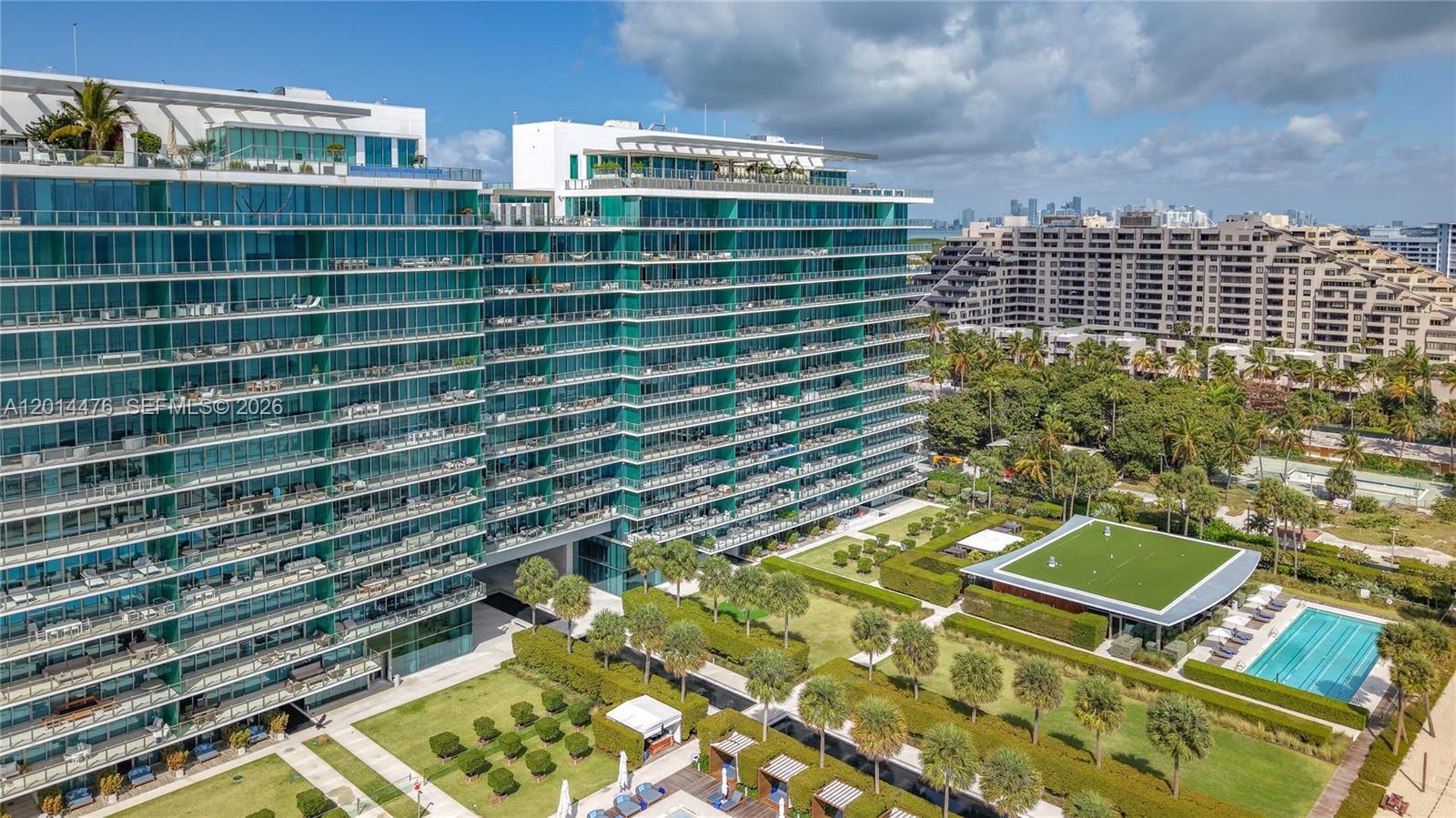 360 Ocean Drive, Unit 1106S Key Biscayne, FL 33149 - Photo 40 of 67 Building Exterior – The modern glass-fronted building is shown with manicured grounds, palm-lined landscaping, and resort-style amenities below. Its expansive balconies and sleek architecture create a striking waterfront presence.