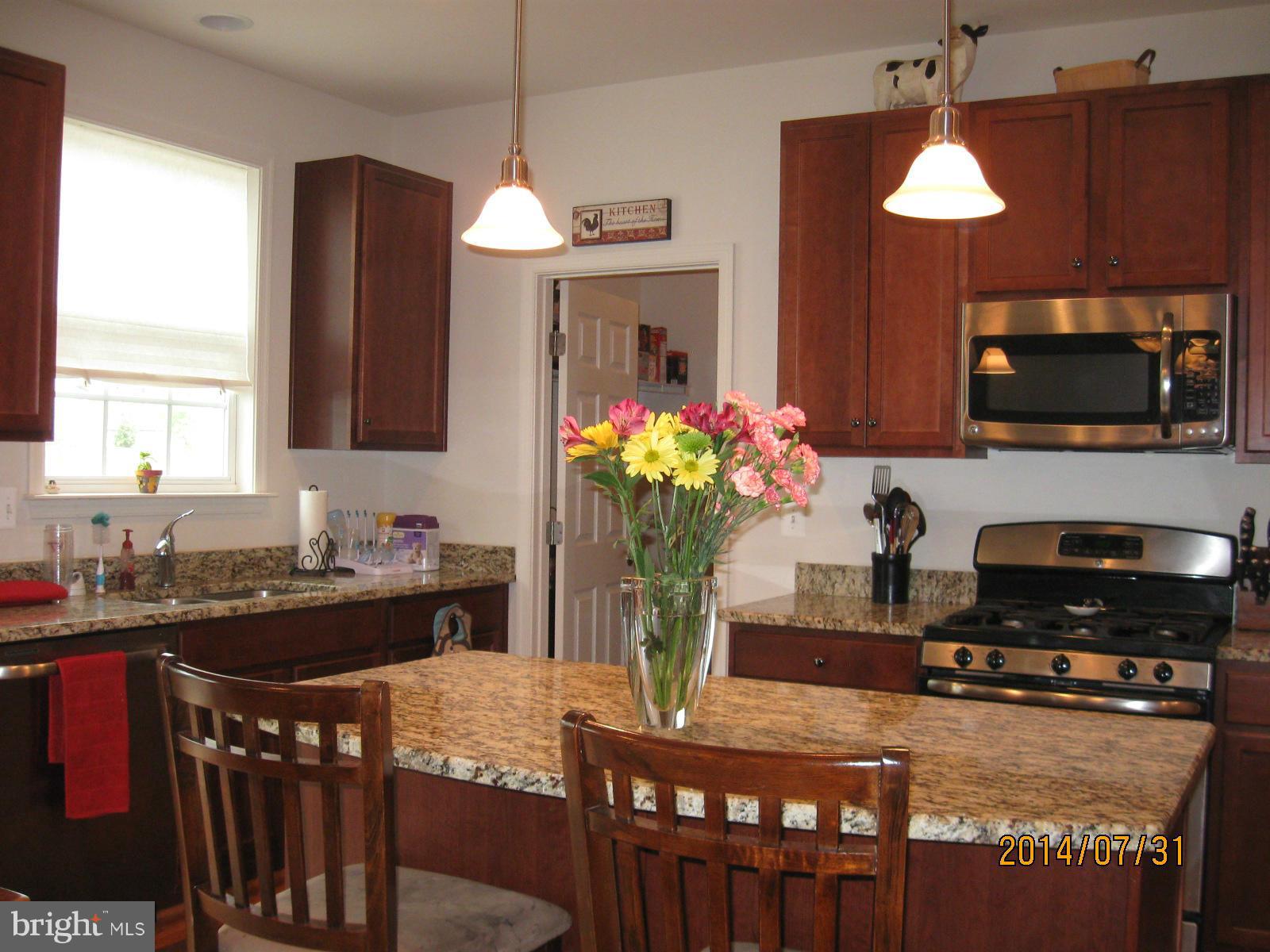 1722 Fletchers Drive Point of Rocks, MD 21777 - Photo 5 of 30 a kitchen with kitchen island granite countertop a stove a sink a refrigerator and a dining table with wooden floor