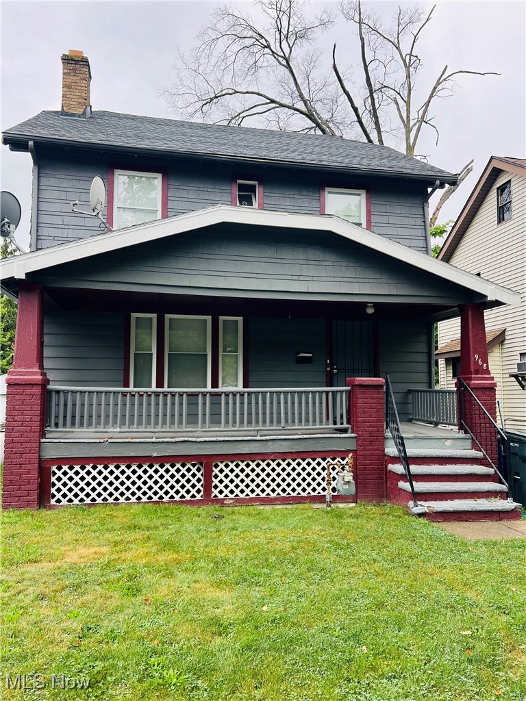 View of front facade with covered porch, a front yard, and a chimney
