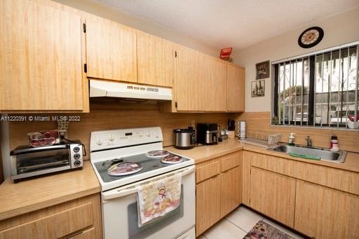 a kitchen with a sink a stove cabinets and a window