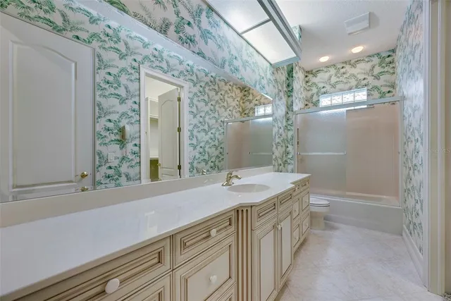 an empty room with windows and chandelier fan