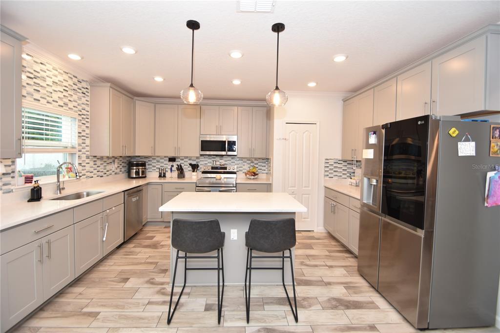 124 Oakleaf Way Palm Coast, FL 32137 - Photo 11 of 36 a kitchen with stainless steel appliances kitchen island granite countertop a refrigerator a sink dishwasher a stove and white cabinets with wooden floor