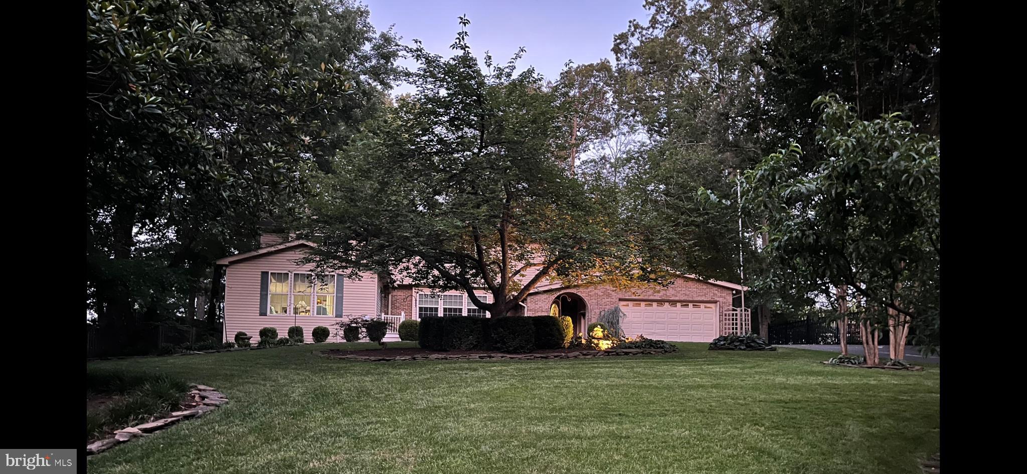 a front view of a house with a garden and trees