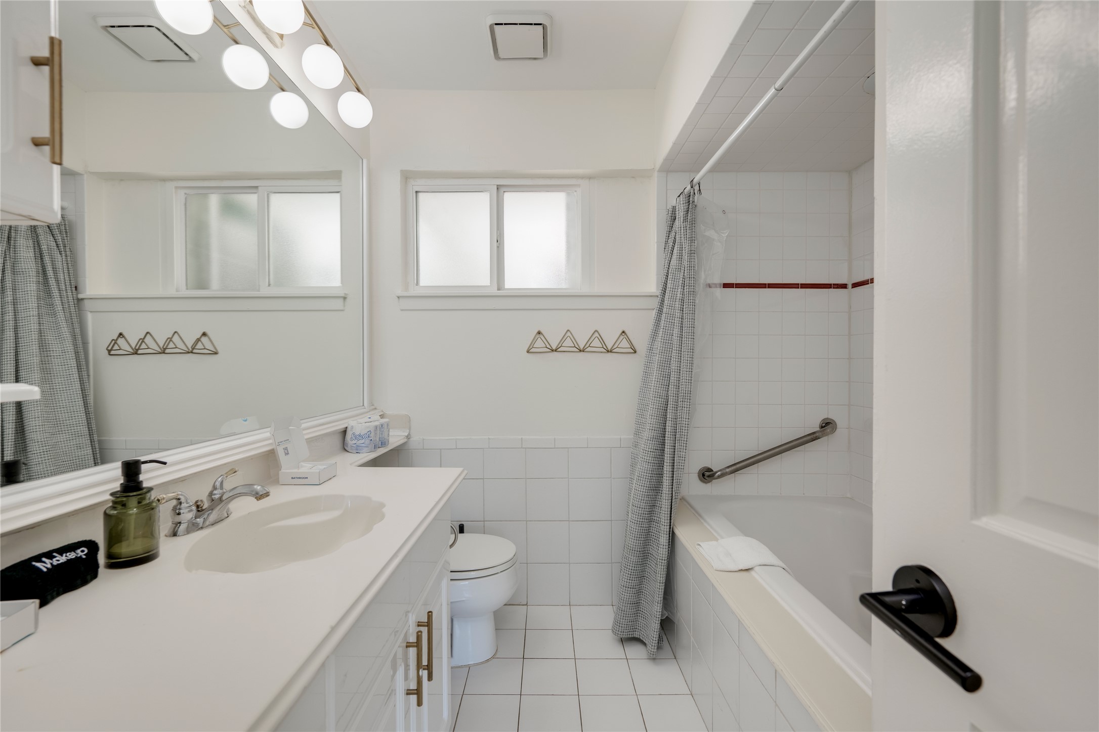 3606 Wilson Street Austin, TX 78704 - Photo 16 of 34 Bathroom featuring vanity, light tile patterned flooring, shower / bath combination with curtain, and tile walls