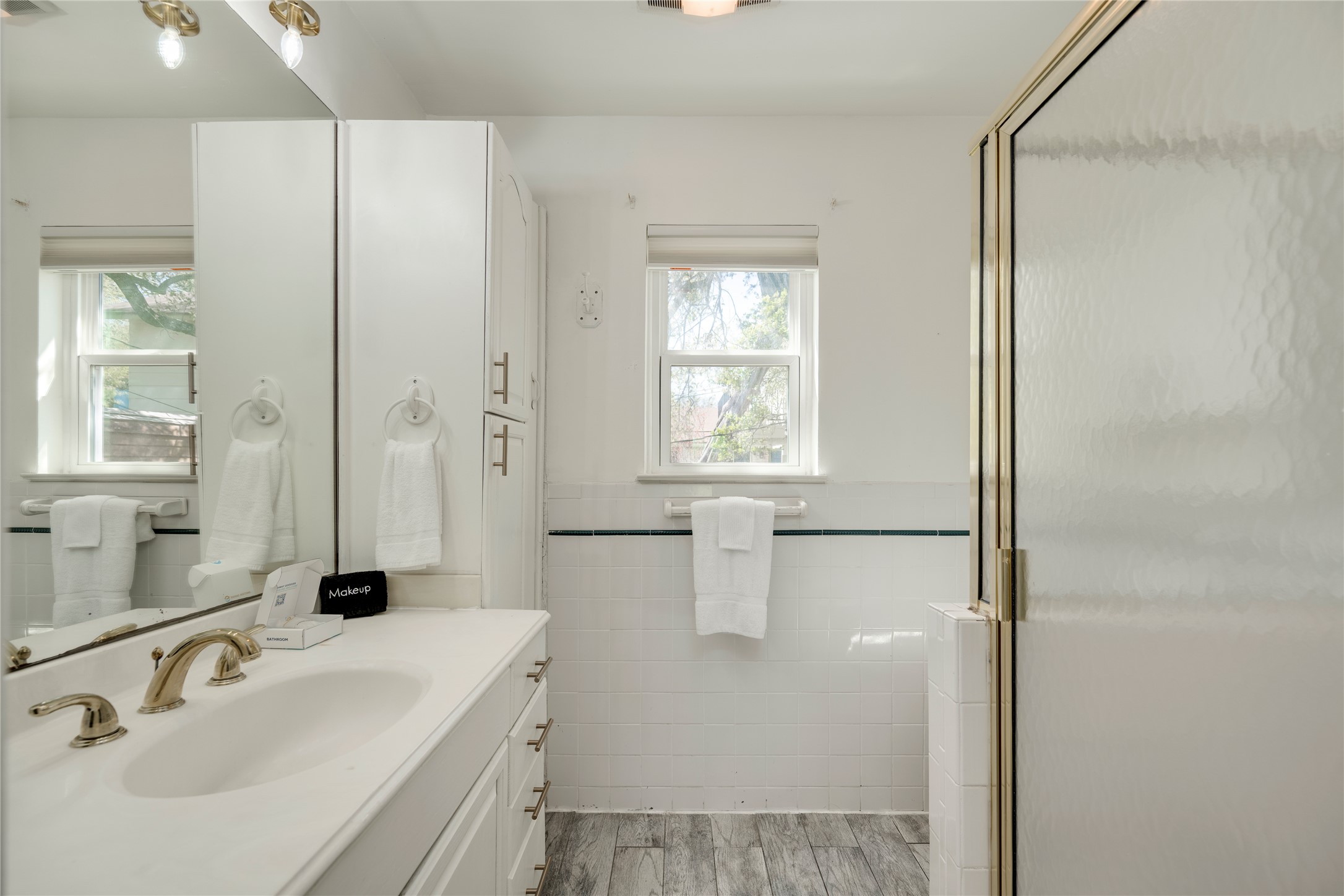 3606 Wilson Street Austin, TX 78704 - Photo 18 of 34 Full bath featuring vanity, tile walls, light wood-type flooring, wainscoting, and a stall shower