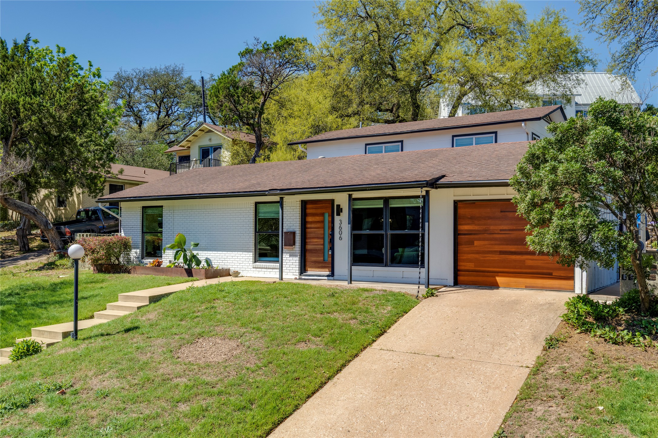 3606 Wilson Street Austin, TX 78704 - Photo 2 of 34 View of front of house with brick siding, a front yard, concrete driveway, an attached garage, and a shingled roof