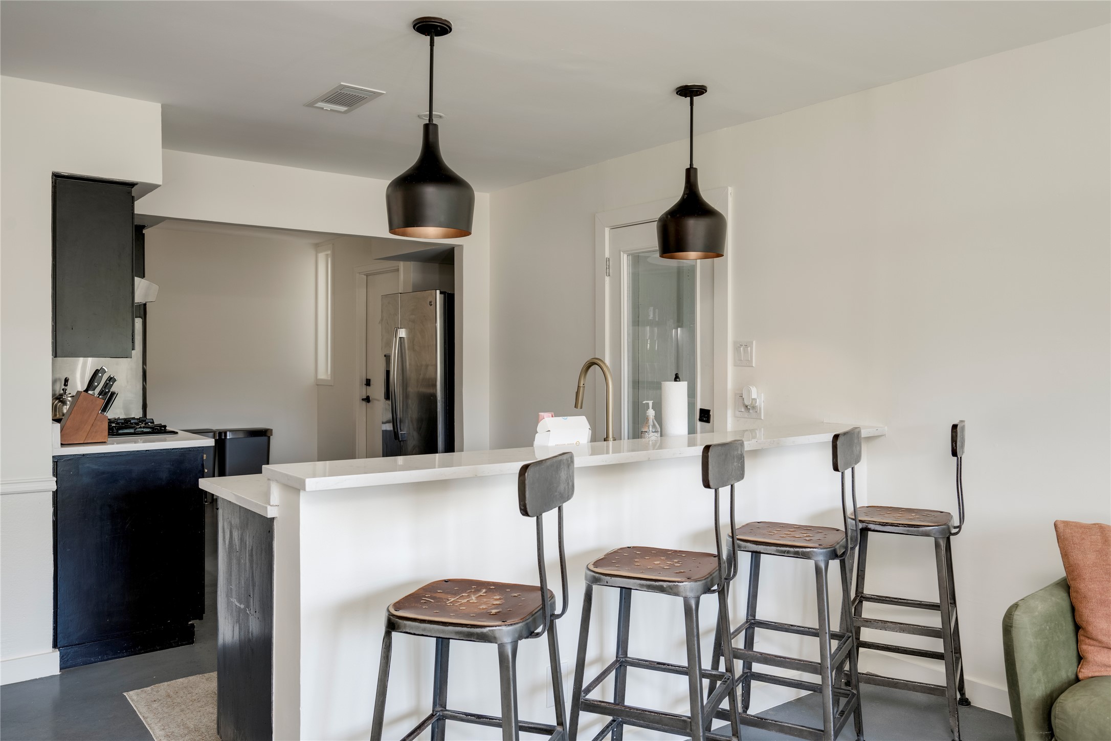 3606 Wilson Street Austin, TX 78704 - Photo 6 of 34 Kitchen with a kitchen bar, stainless steel fridge with ice dispenser, finished concrete floors, decorative light fixtures, and a peninsula