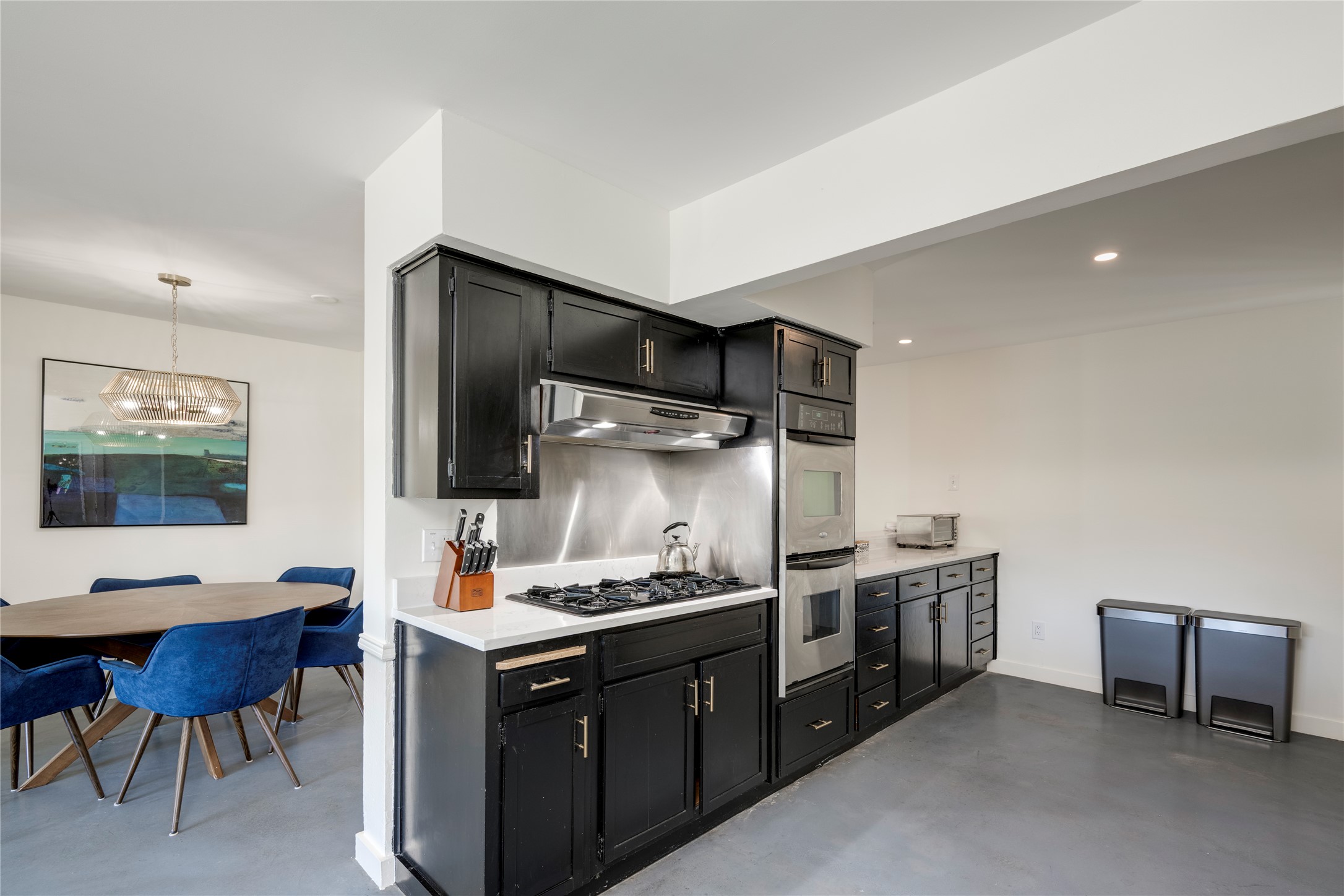 3606 Wilson Street Austin, TX 78704 - Photo 7 of 34 Kitchen with dark cabinets, finished concrete flooring, stainless steel appliances, and hanging lights
