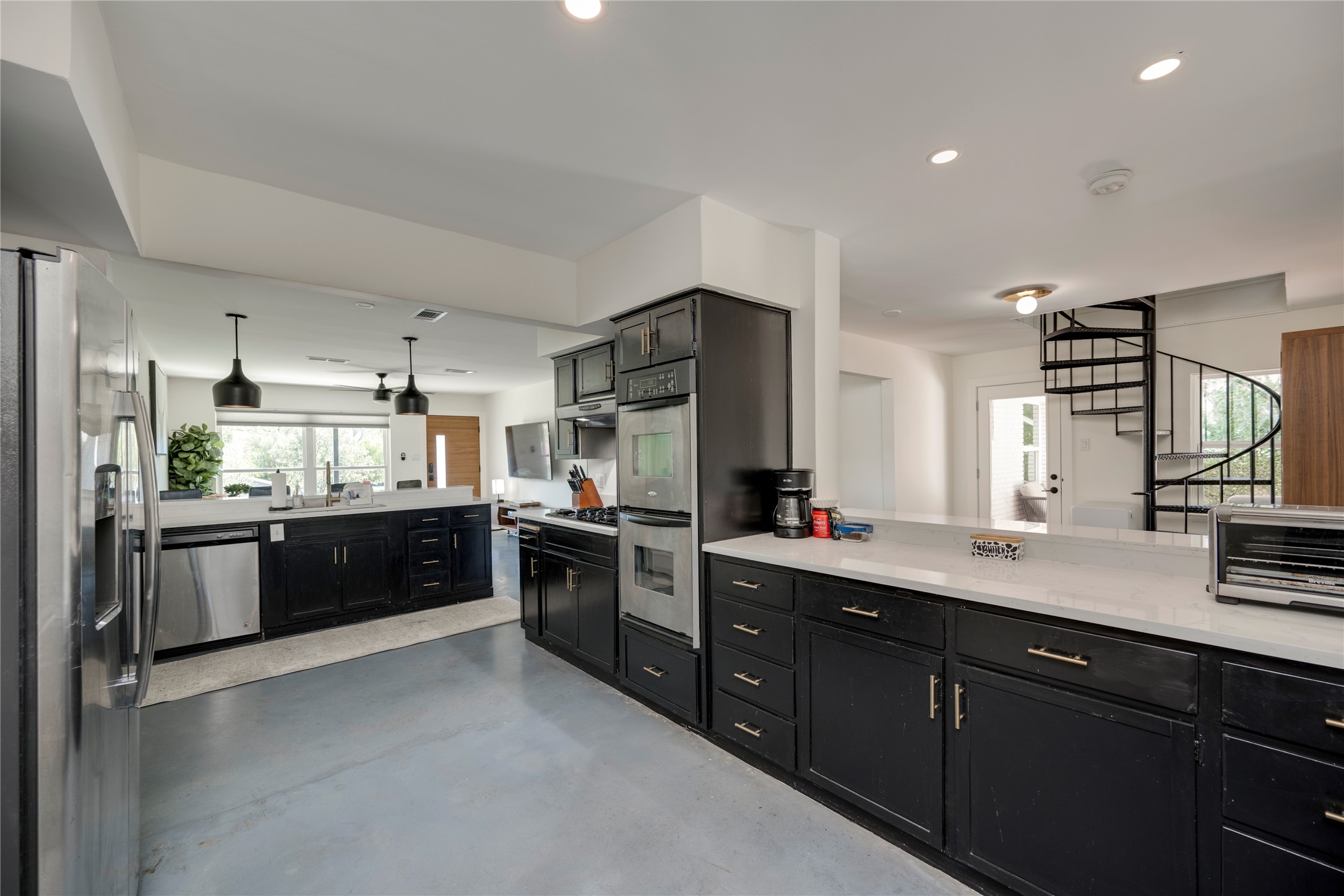 3606 Wilson Street Austin, TX 78704 - Photo 8 of 34 Kitchen with dark cabinets, stainless steel appliances, finished concrete flooring, a peninsula, and light stone countertops