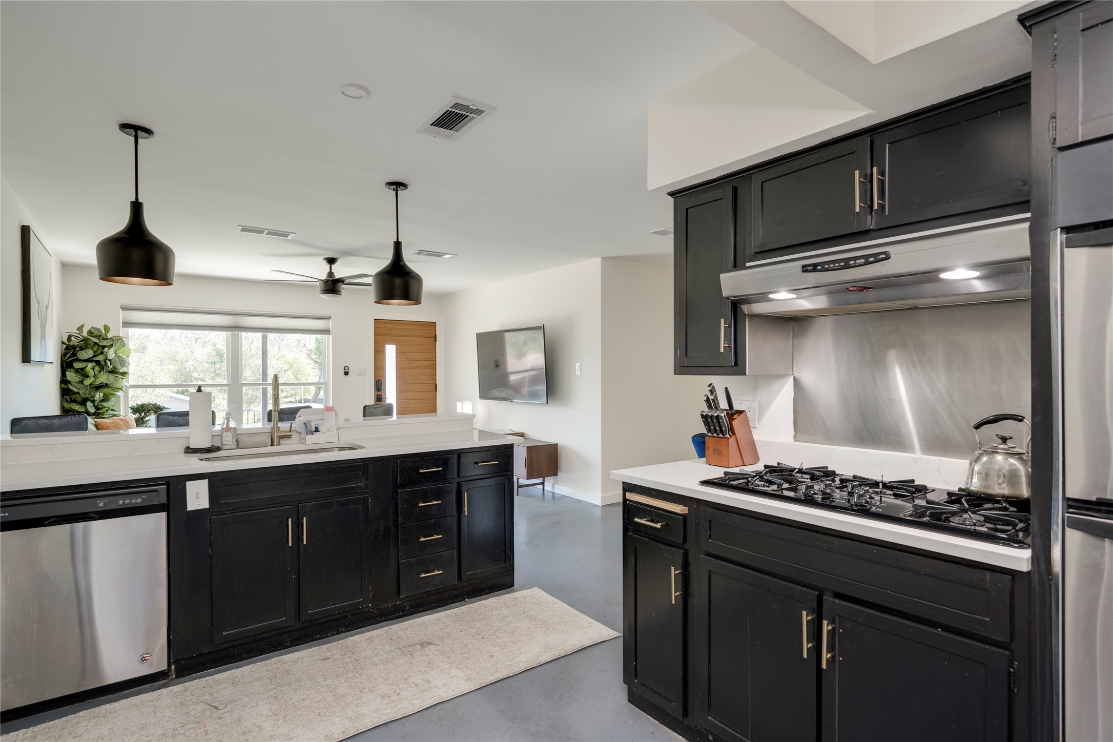 3606 Wilson Street Austin, TX 78704 - Photo 10 of 34 Kitchen with concrete flooring, dark cabinetry, stainless steel dishwasher, and black gas cooktop