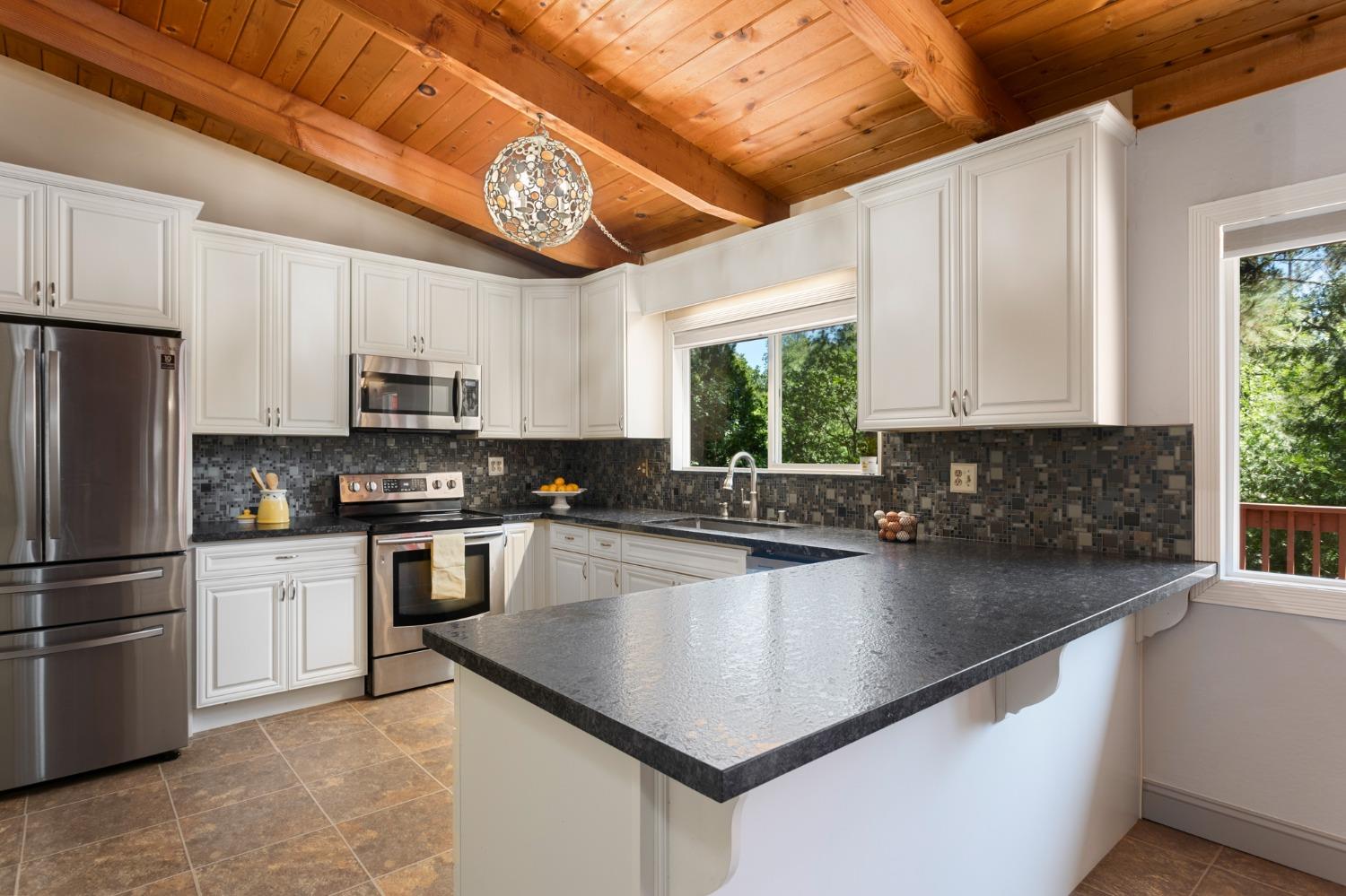 a kitchen with kitchen island granite countertop a stove a sink a refrigerator a window and cabinets