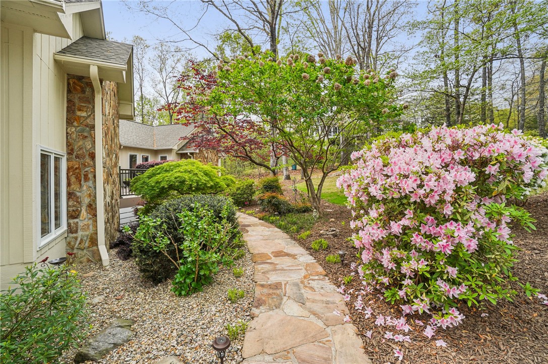 120 Beacon Ridge Circle Salem, SC 29676 - Photo 2 of 48 A stone pathway leads to a beautiful residence surrounded by lush greenery and vibrant flowers.