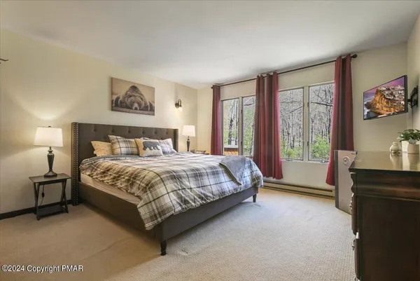 a bedroom with a bed painting on wall and a large window